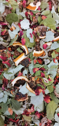 Close-up of a loose herbal blend of dried orange peel, pale green mint leaves and pink petals.
