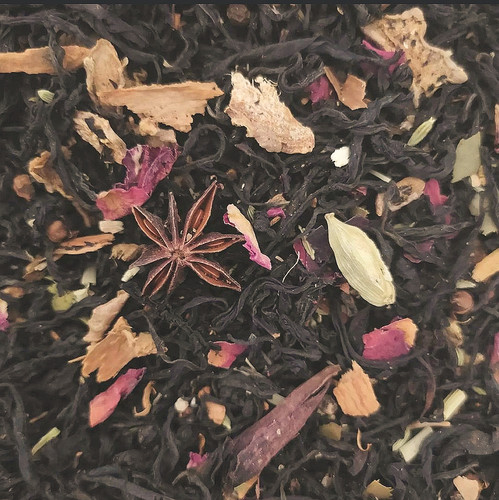Close-up of loose masala chai: black tea leaves with star anise, cinnamon bark, cardamom pods and petals.