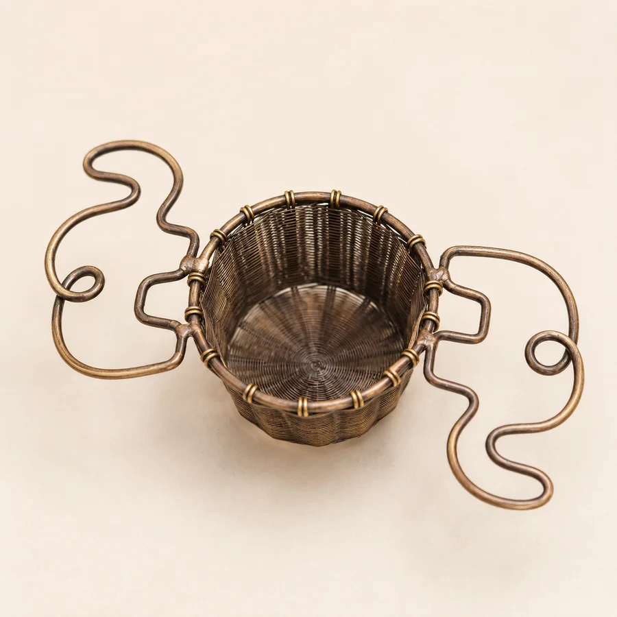 Handcrafted brass elephant tea strainer, a brass basket with two elephant-shaped wire handles