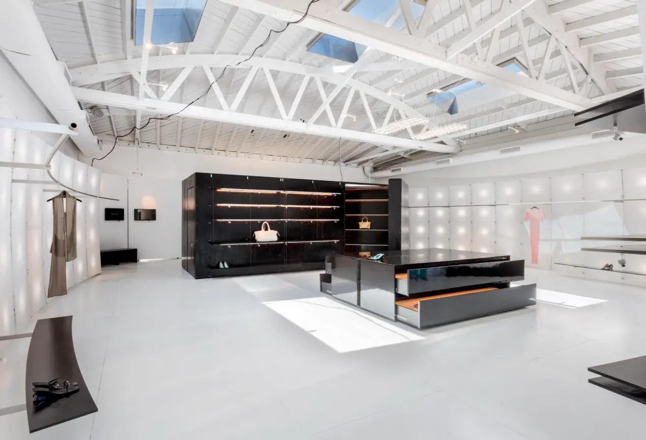 Paloma Wool store with a black lit shelving block, a glossy black cash wrap with pull-out drawers, and curved display benches