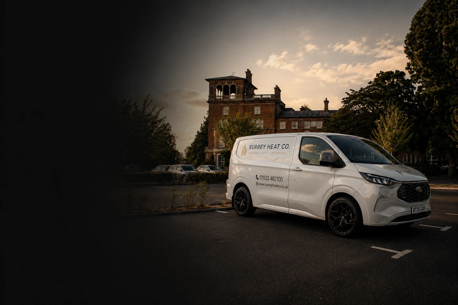 White Surrey Heat Co. service van parked in front of a large historic brick building at sunset.