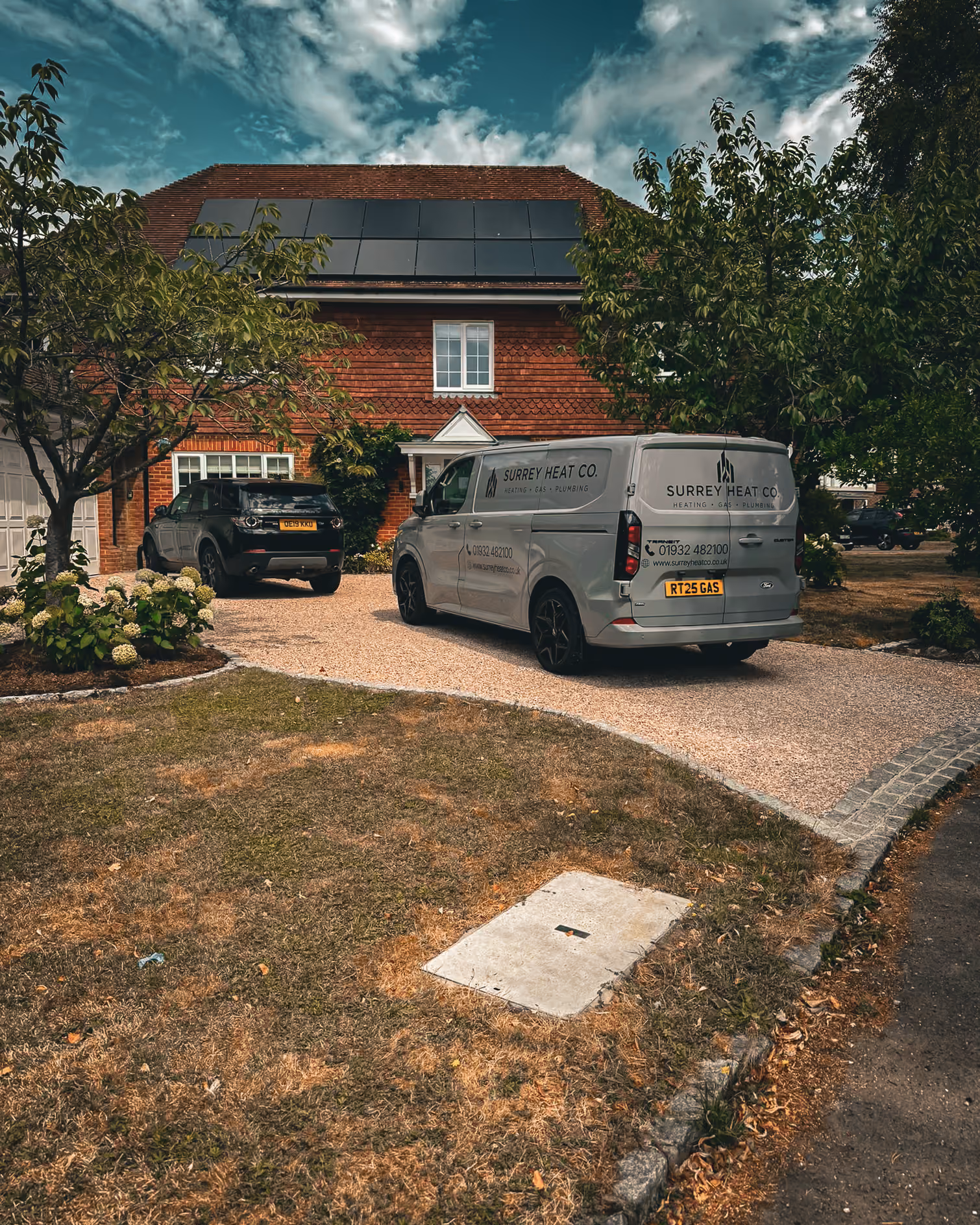 Surrey Heat Co. van parked on a driveway of a red brick house with solar panels on the roof.