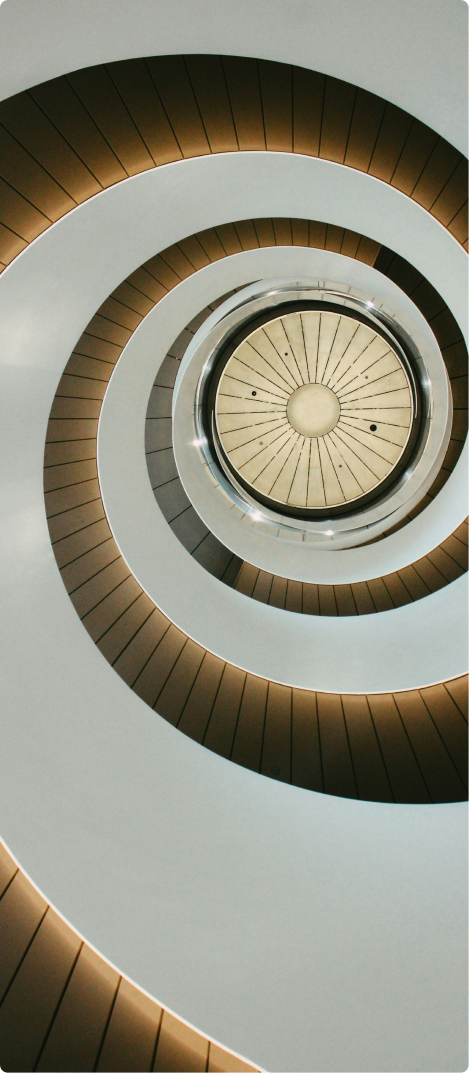 Looking up at a modern spiral staircase with curved railings and radial steps.