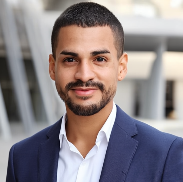 Portrait of a smiling man with short hair, beard, in a blue suit jacket and white shirt.
