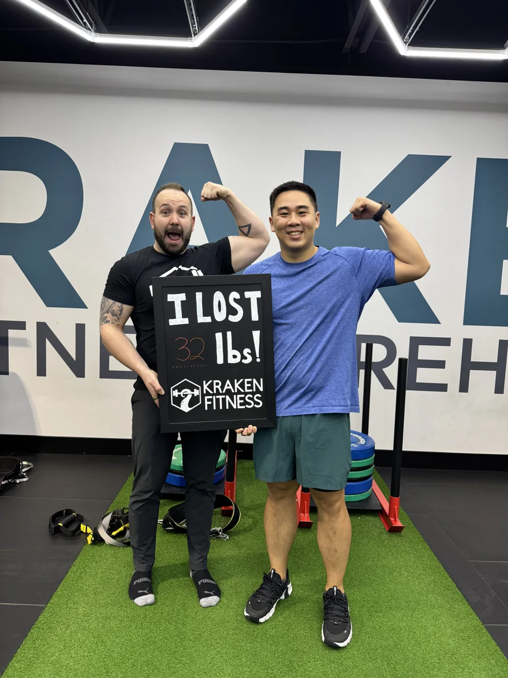 Brandon holding his I lost 32 lbs chalkboard at Kraken Fitness