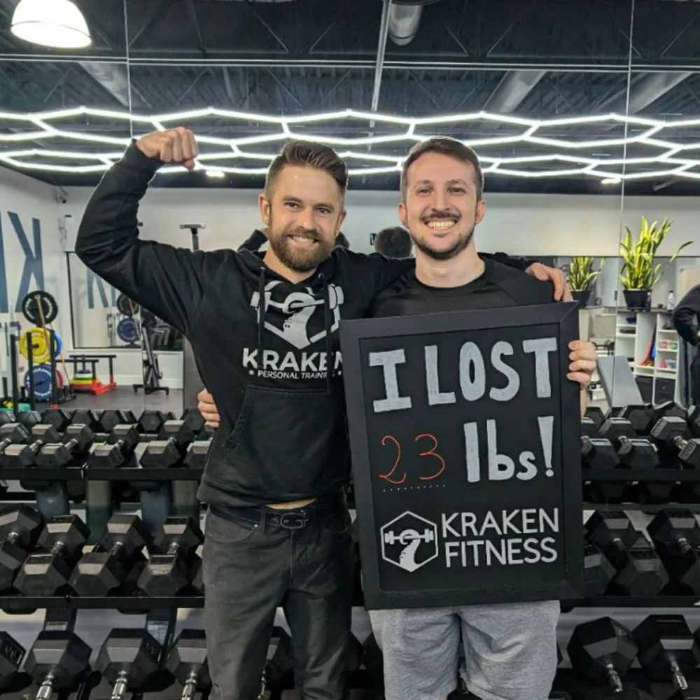 Marco holding an I lost 23 lbs chalkboard at Kraken Fitness