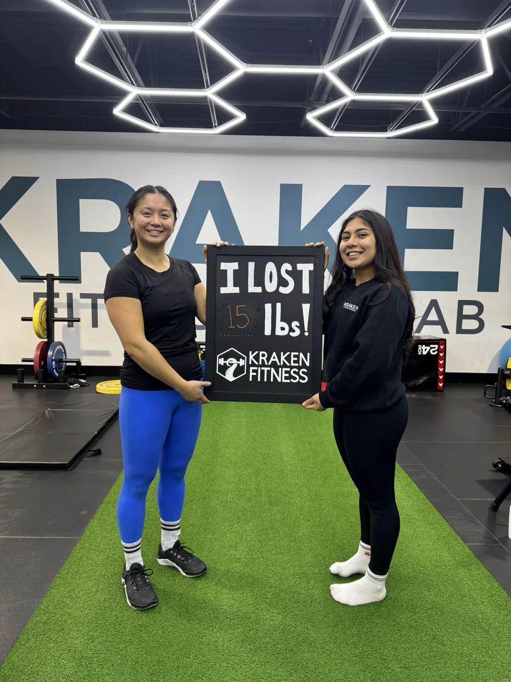 Cecilia holding an I lost 15 lbs chalkboard at Kraken Fitness