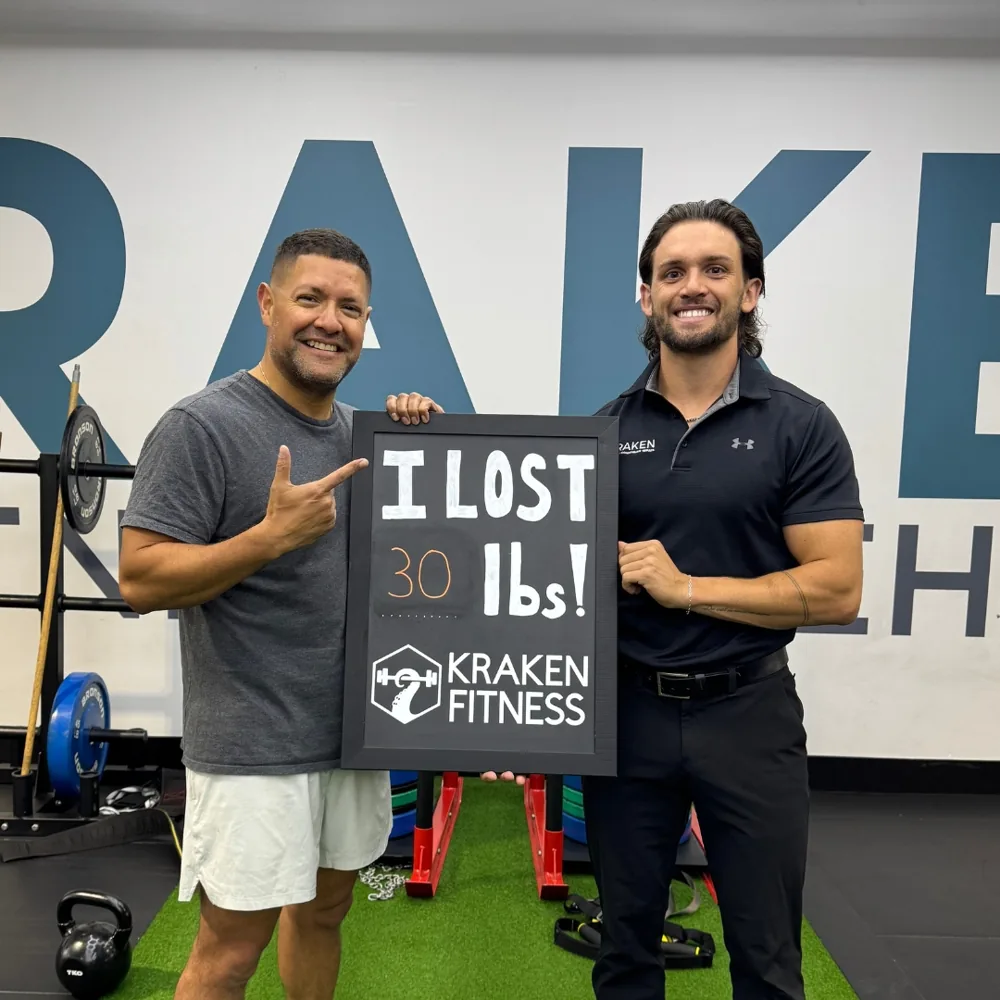 Luis holding an I lost 30 lbs chalkboard at Kraken Fitness