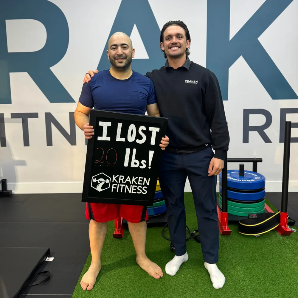 Hossein holding an I lost 20 lbs chalkboard at Kraken Fitness