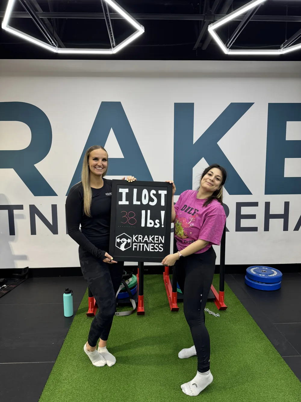 Cecilia holding an I lost 38 lbs chalkboard at Kraken Fitness
