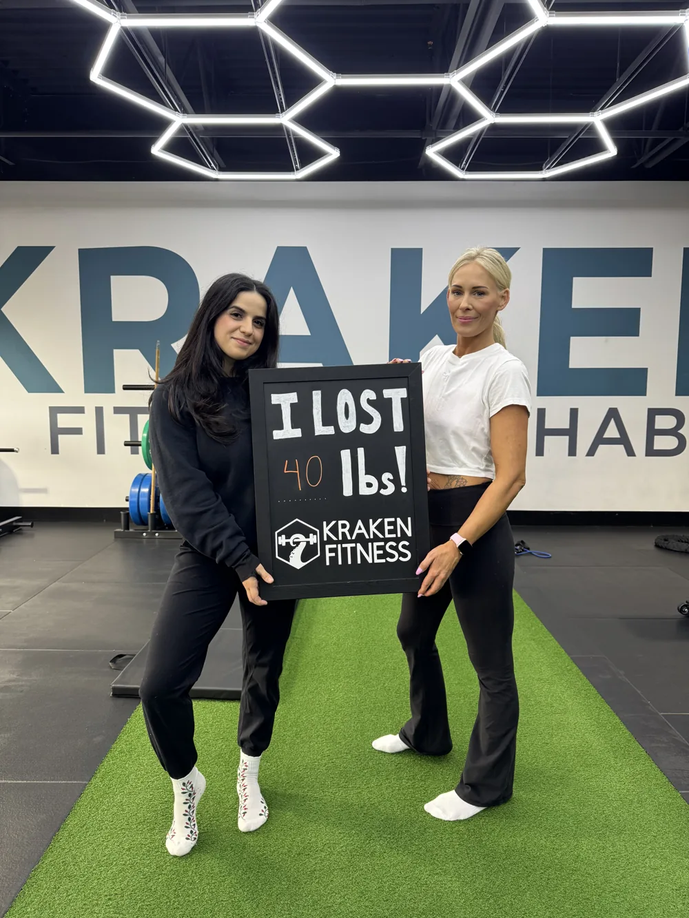 Christina holding an I lost 40 lbs chalkboard at Kraken Fitness