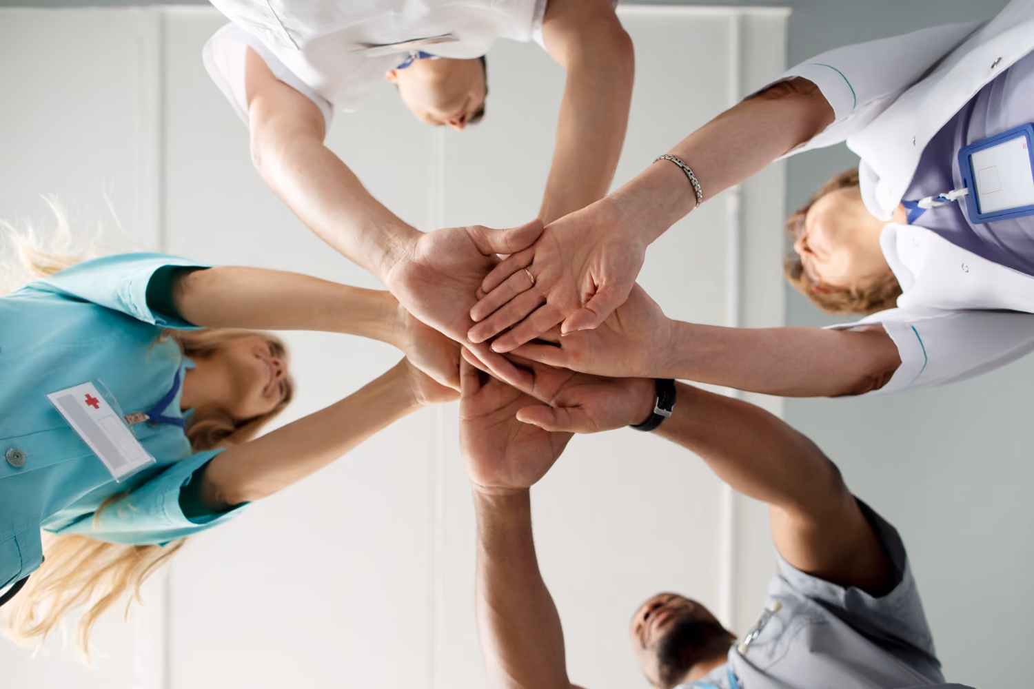 Hände eines Pflegeteams liegen übereinander