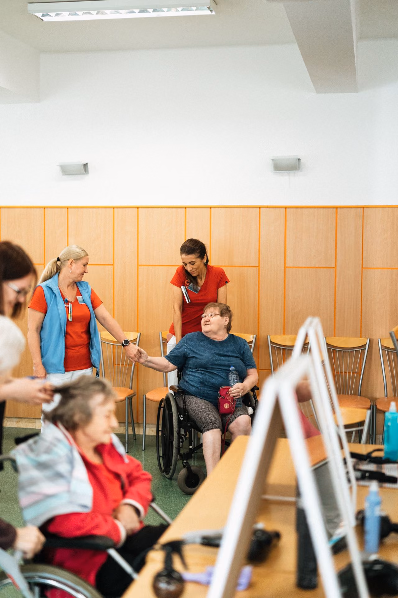 Pflegekraft begleitet Bewohner im Rollstuhl durch einen Gemeinschaftsraum