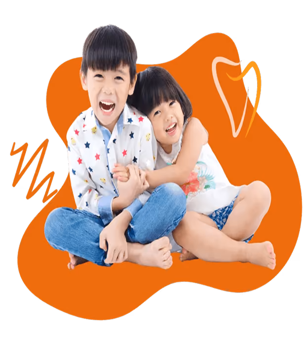 Smiling young boy and girl sitting barefoot on floor, hugging with an orange abstract background.
