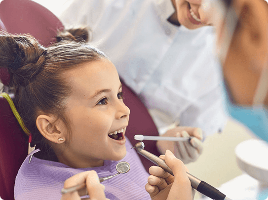 Smiling woman reclined in a dental chair, interacting with a dentist wearing blue gloves.