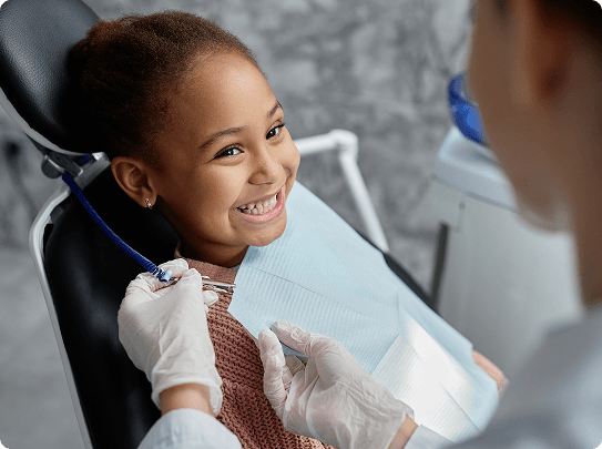 Smiling woman reclined in a dental chair, interacting with a dentist wearing blue gloves.