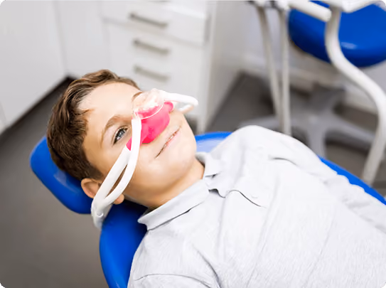 Smiling man sitting in a dental chair giving a thumbs-up in a bright dental office.
