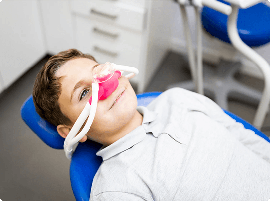 Smiling man sitting in a dental chair giving a thumbs-up in a bright dental office.
