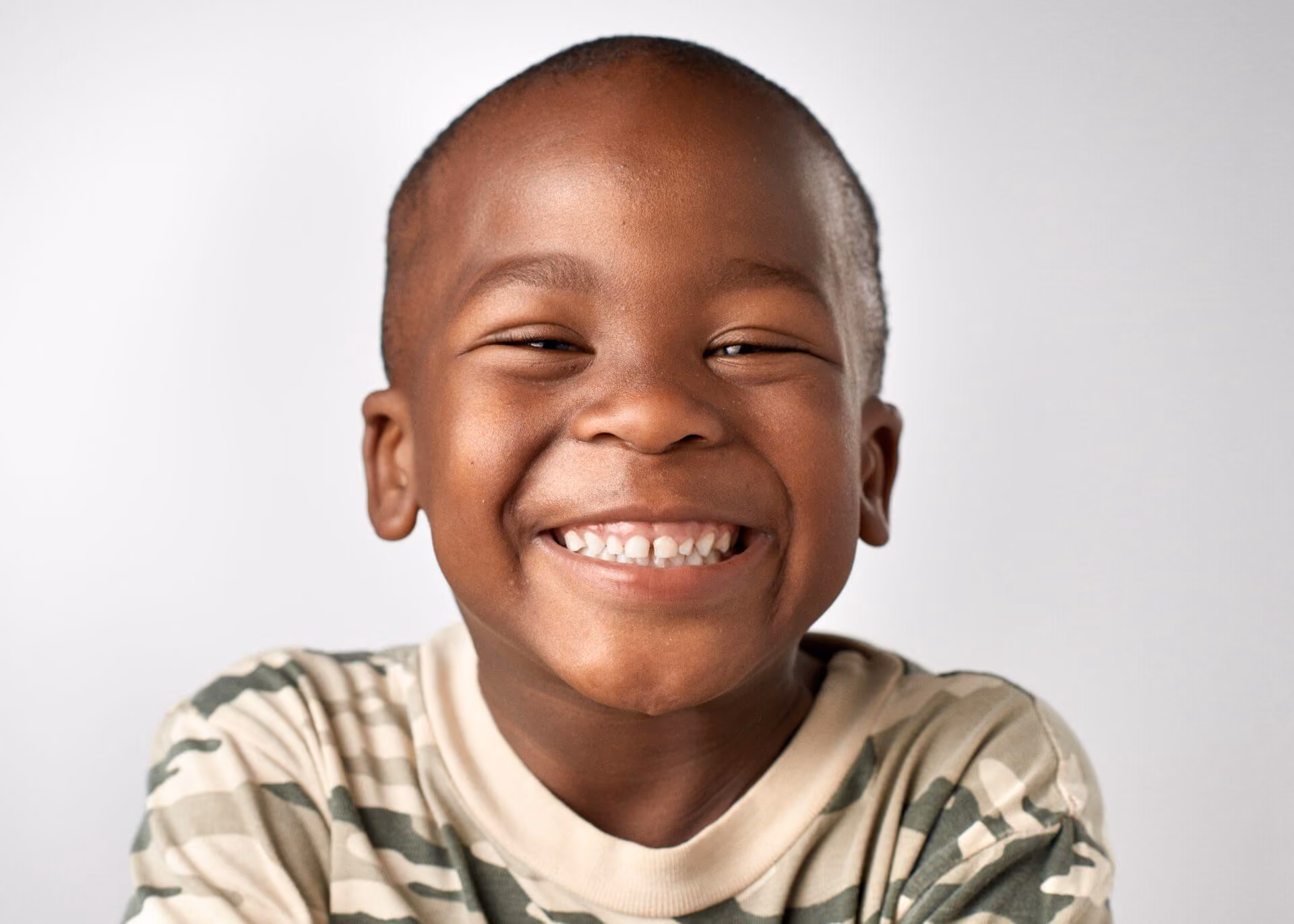Smiling man sitting in a dental chair giving a thumbs-up in a bright dental office.