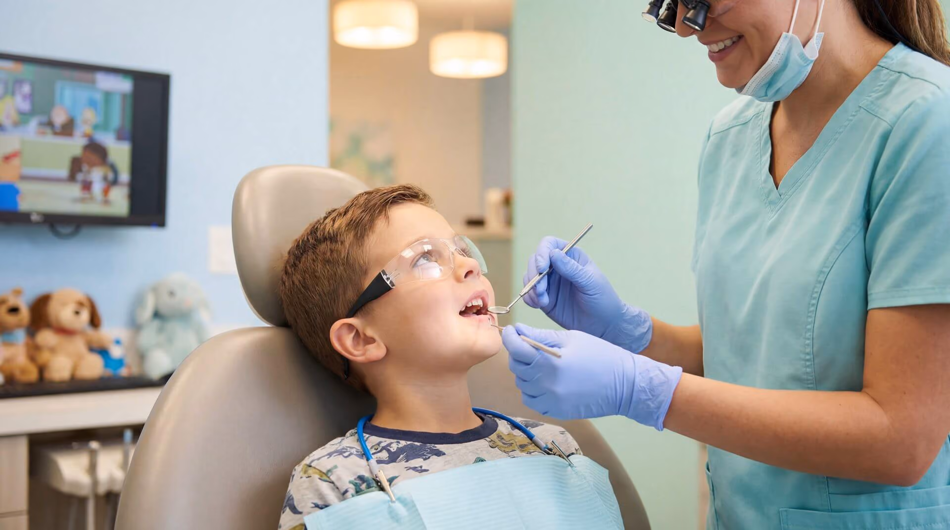 Smiling man sitting in a dental chair giving a thumbs-up in a bright dental office.