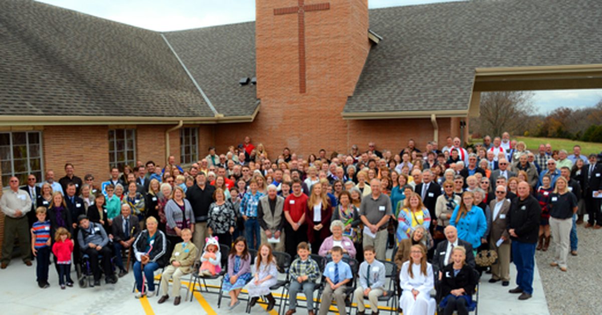 The members of Trinity Lutheran Church in Paola, Kansas, stand outside their church building to pose for a photo together.