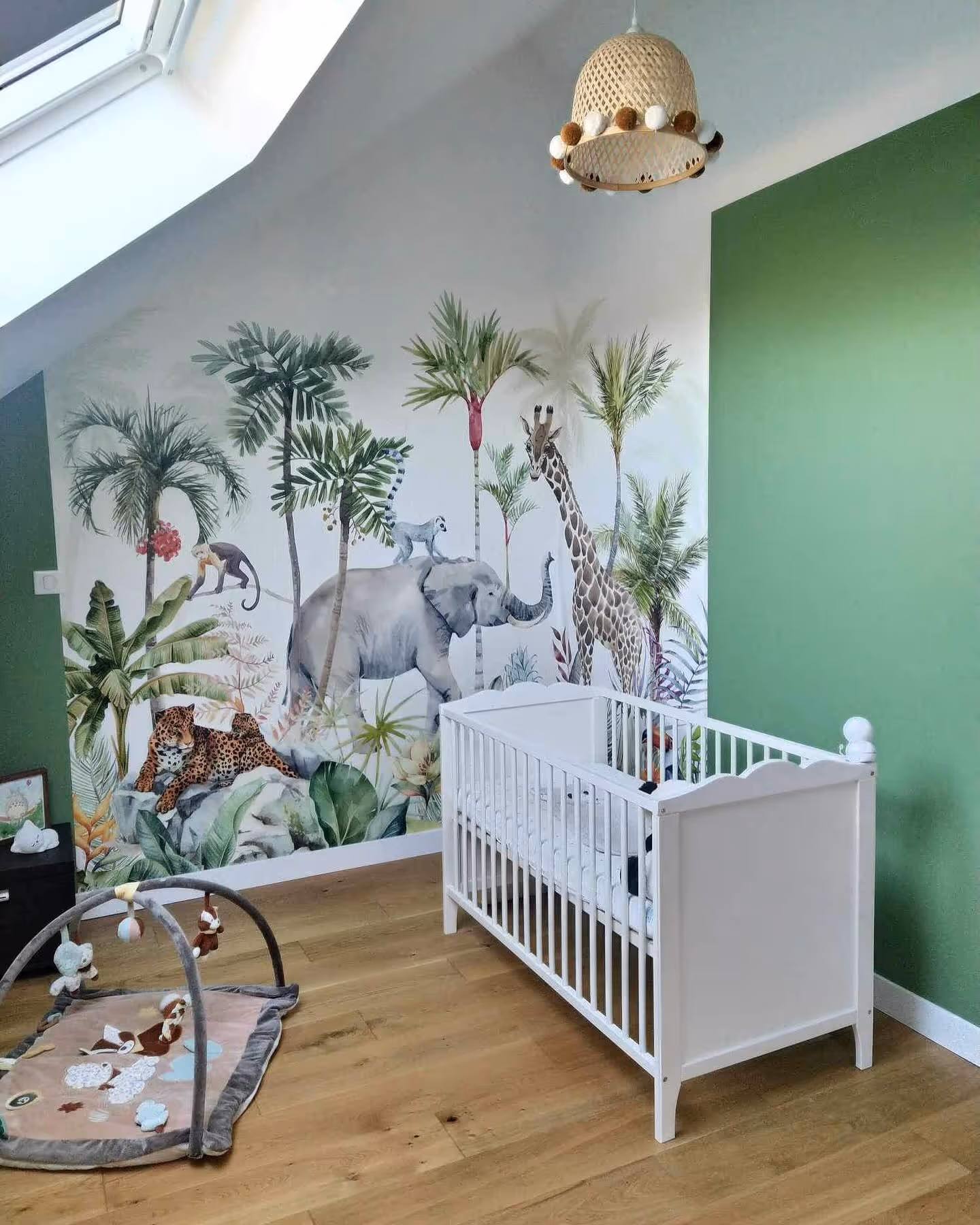 Chambre d'enfant avec lit blanc, tapis de jeu et mur décoré d'animaux africains et de plantes.