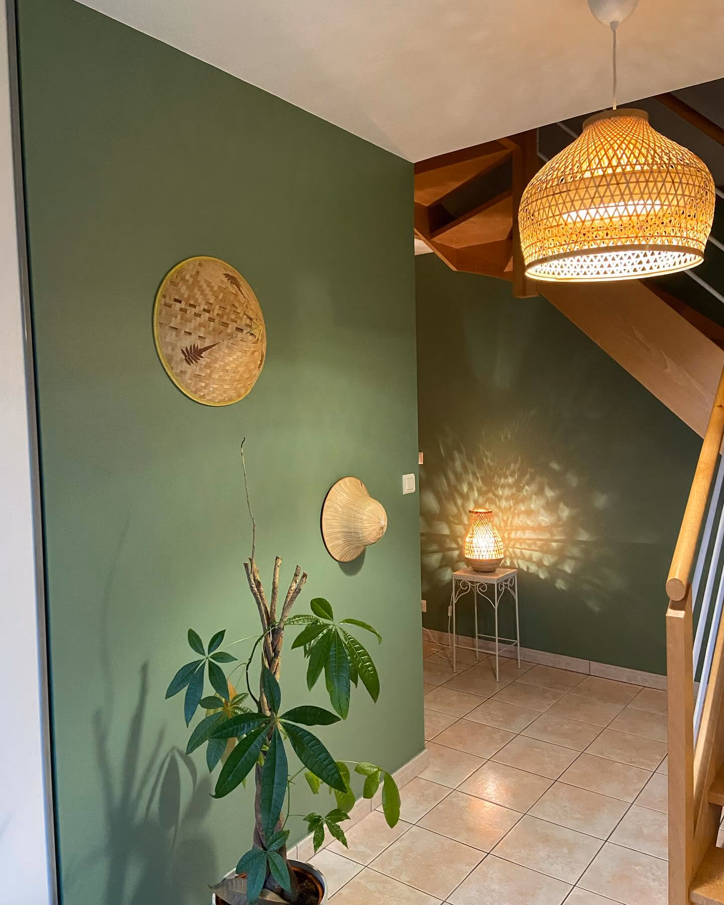 Salon avec deux fauteuils beige, cheminée encadrée de bois, TV sur meuble blanc et murs rouges.