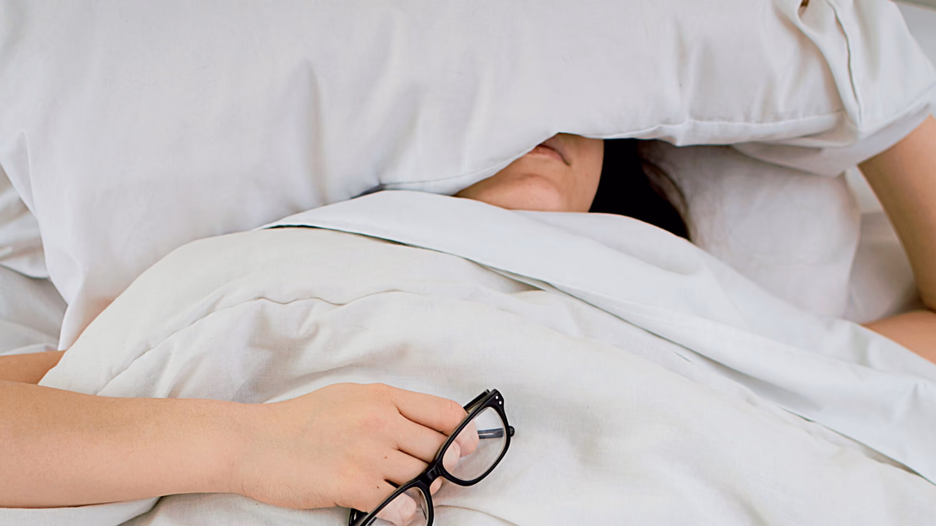 Personne au repos dans une chambre sombre, illustrant les difficultés de sommeil et les rythmes biologiques.