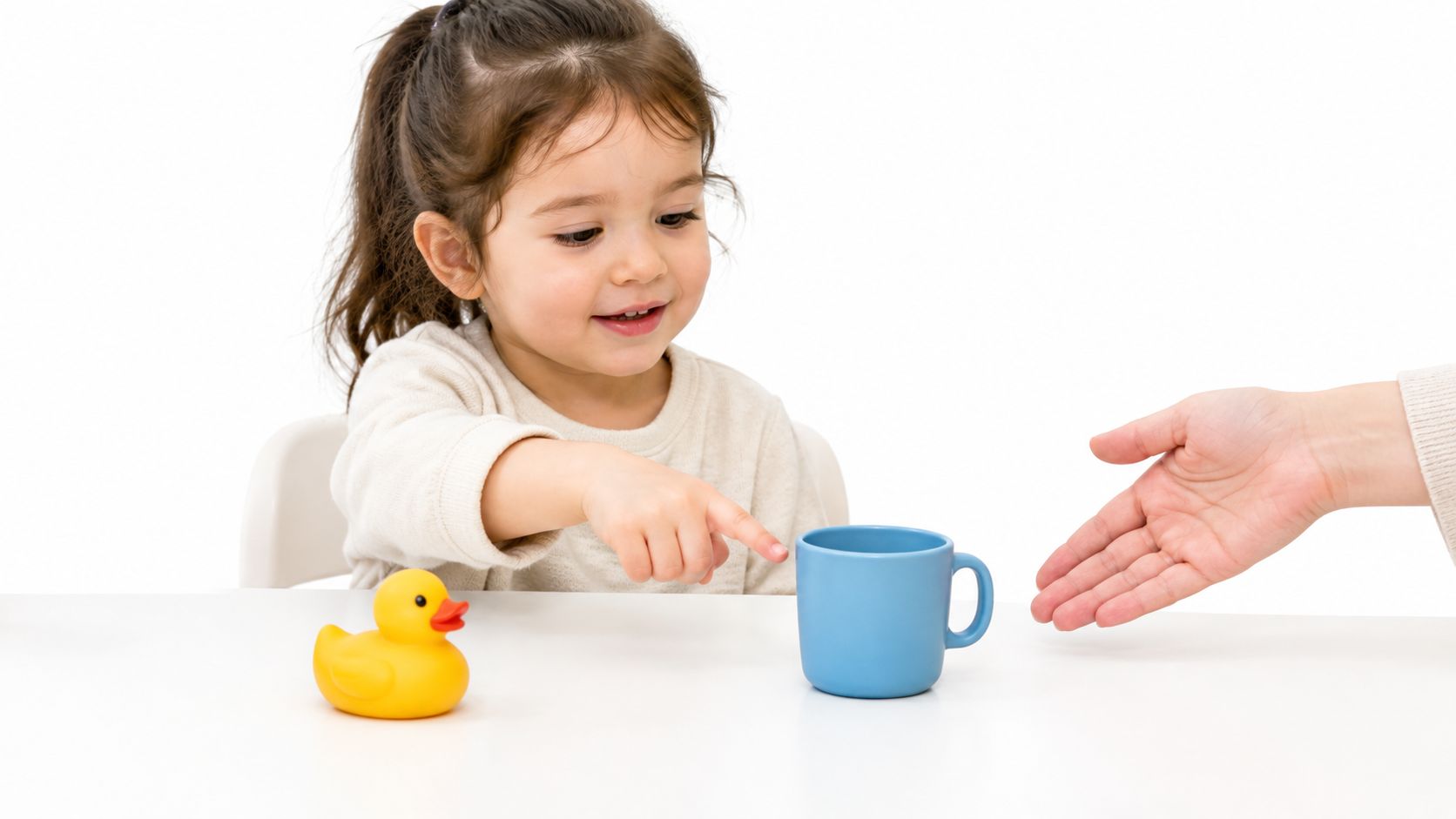A young girl participating in discrete trial training, pointing at a blue cup on a table.