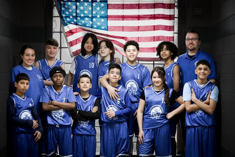 Middle school basketball team posing in blue uniforms with American flag