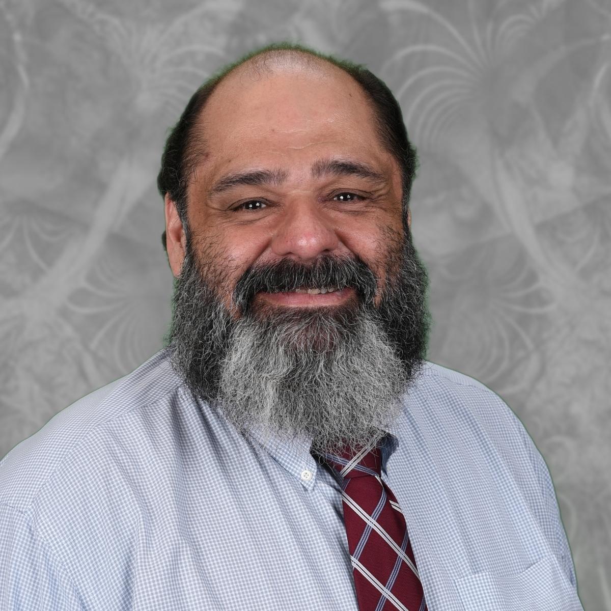 Jorge Suarez staff portrait smiling in shirt and tie