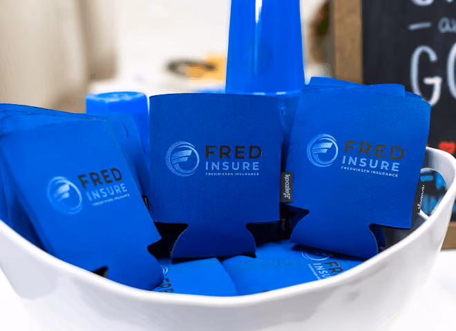 Blue insulated can holders with Fred Insure logo in a white bowl.
