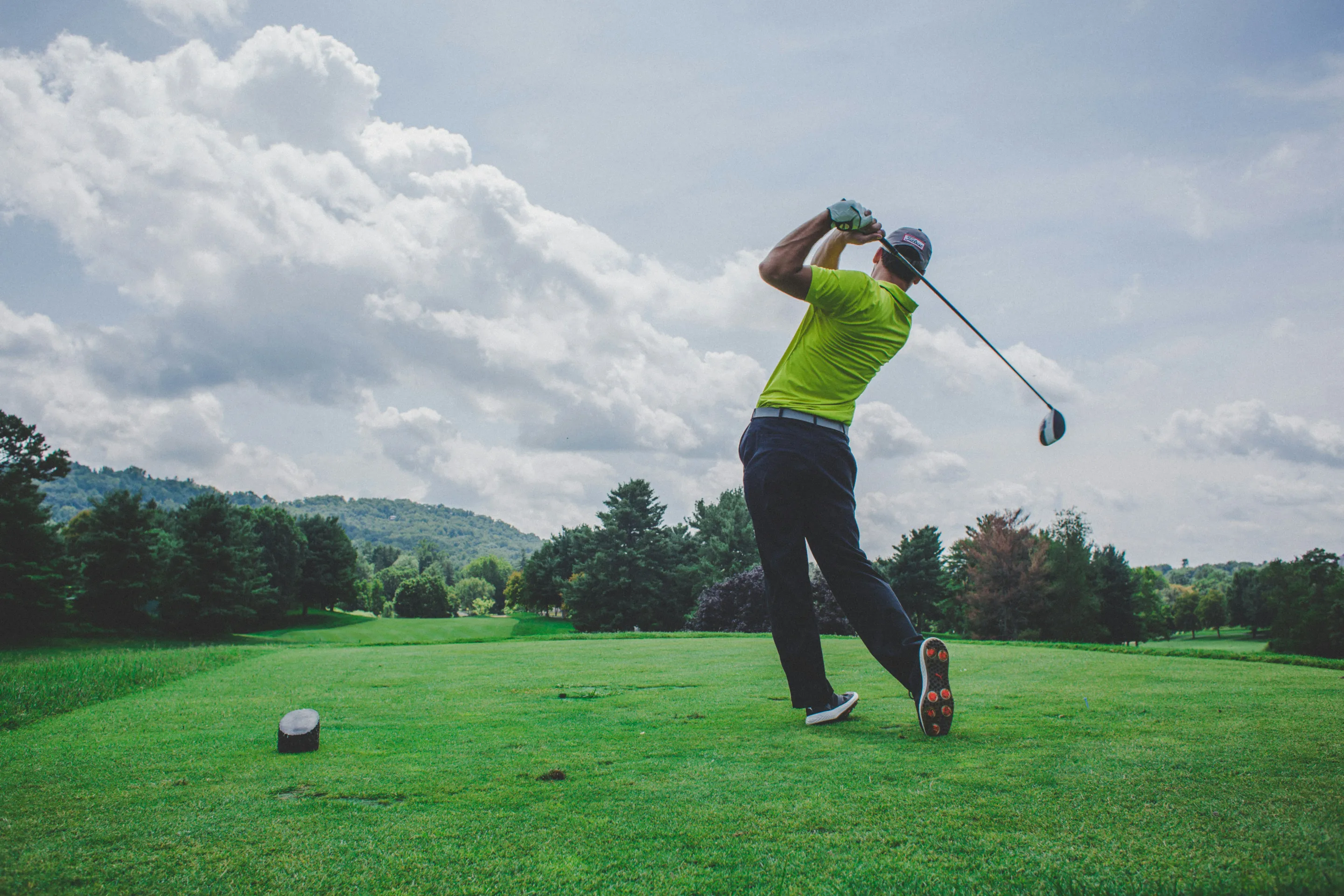 A golfer mid-swing on a green golf course