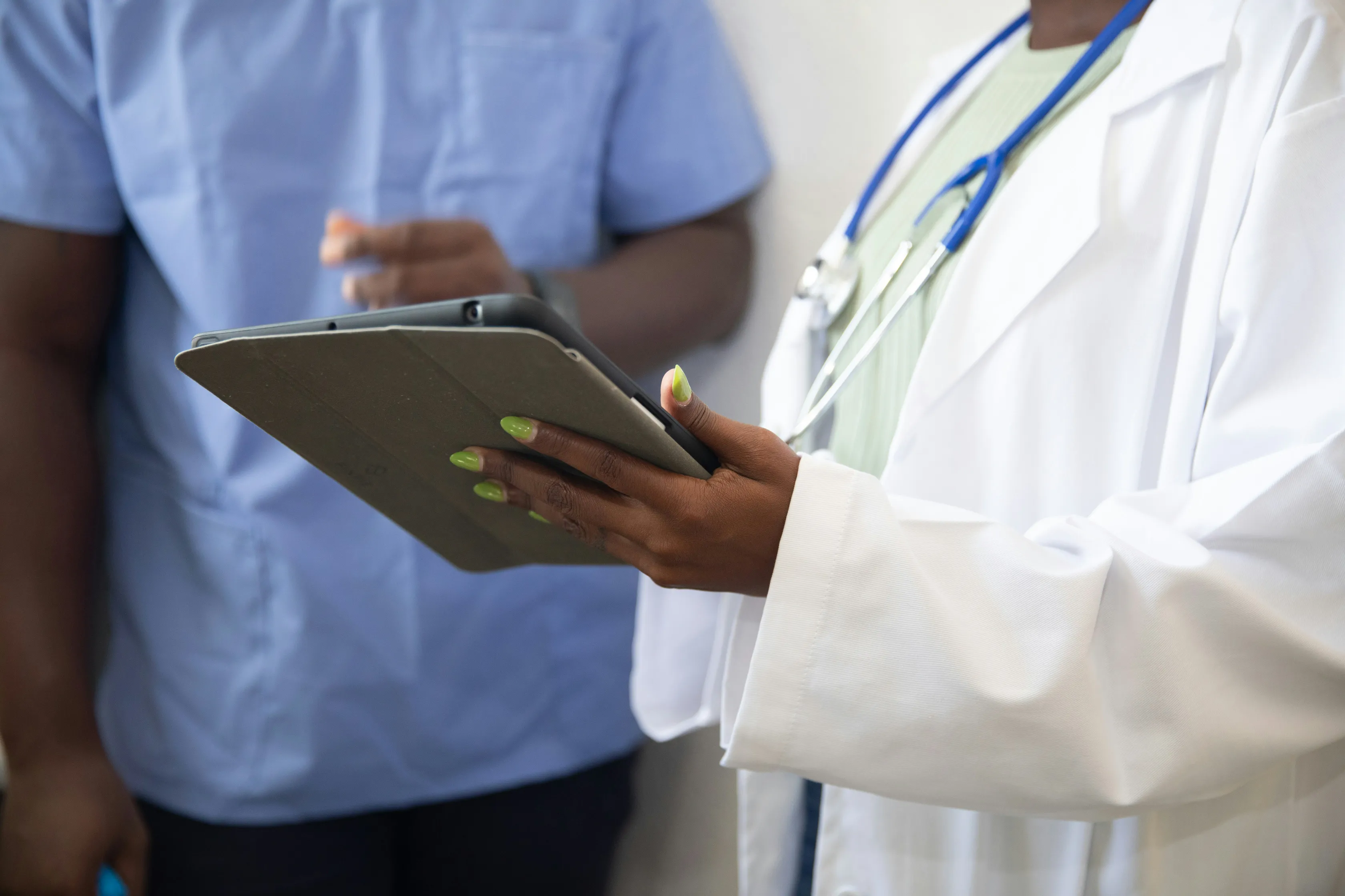 A healthcare worker in a white coat holding a tablet