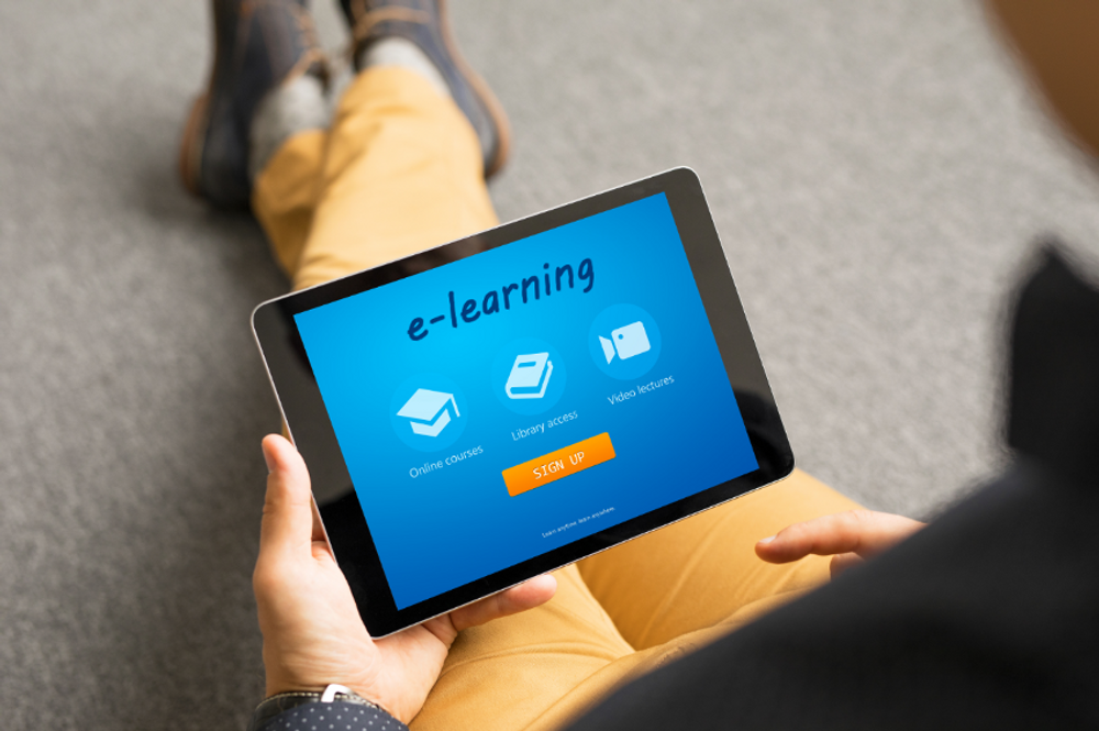 uma pessoa segurando um tablet com a escrita "e-learning" na tela