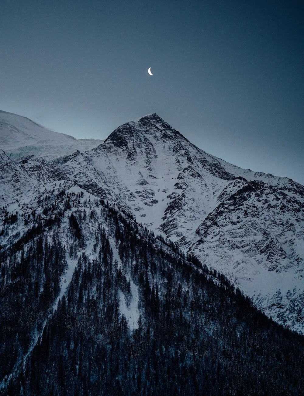 A snow-capped mountain peak beneath a crescent moon at dusk, representing the foundation of SummitView Holdings' capital formation and structuring.