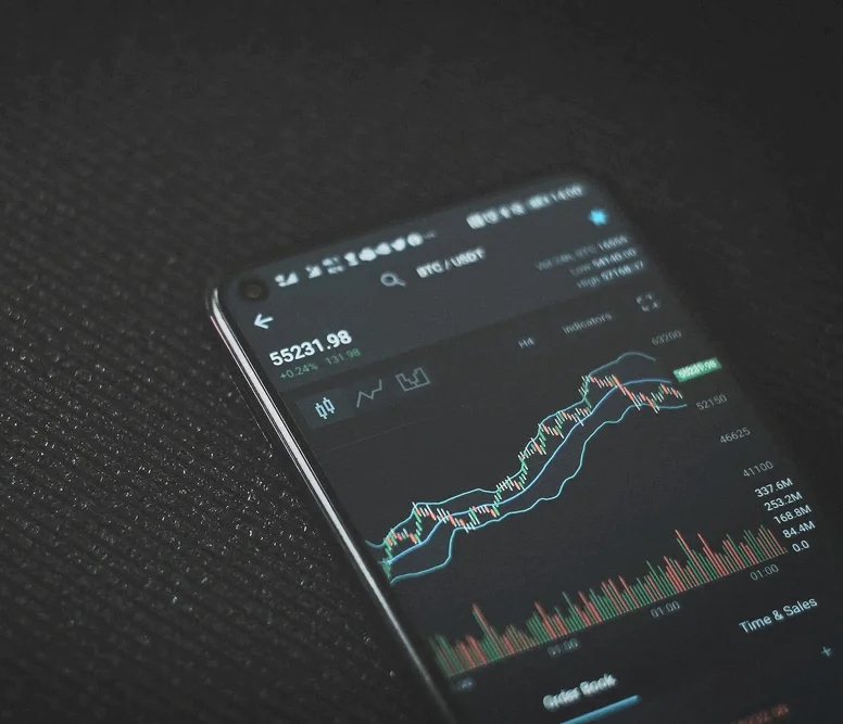 Smartphone displaying a live trading chart with rising and falling price data, representing a scalable, data-driven operating platform.