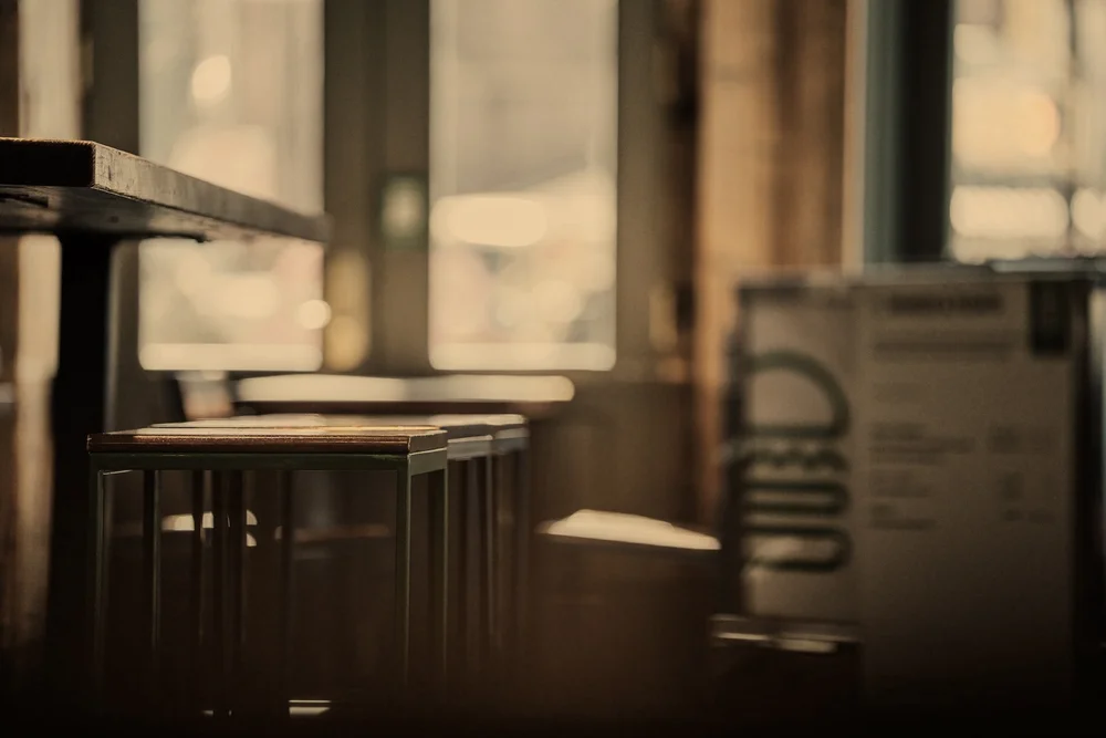 Softly lit, blurred cafe interior with wooden stools and tables, representing a franchise location built for expansion.