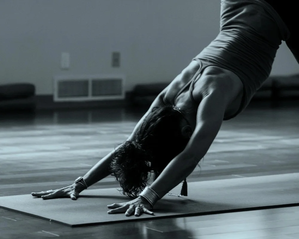 Black-and-white photo of a woman in a yoga pose on a studio floor, illustrating SummitView Holdings' disciplined approach to franchise brand partnerships.