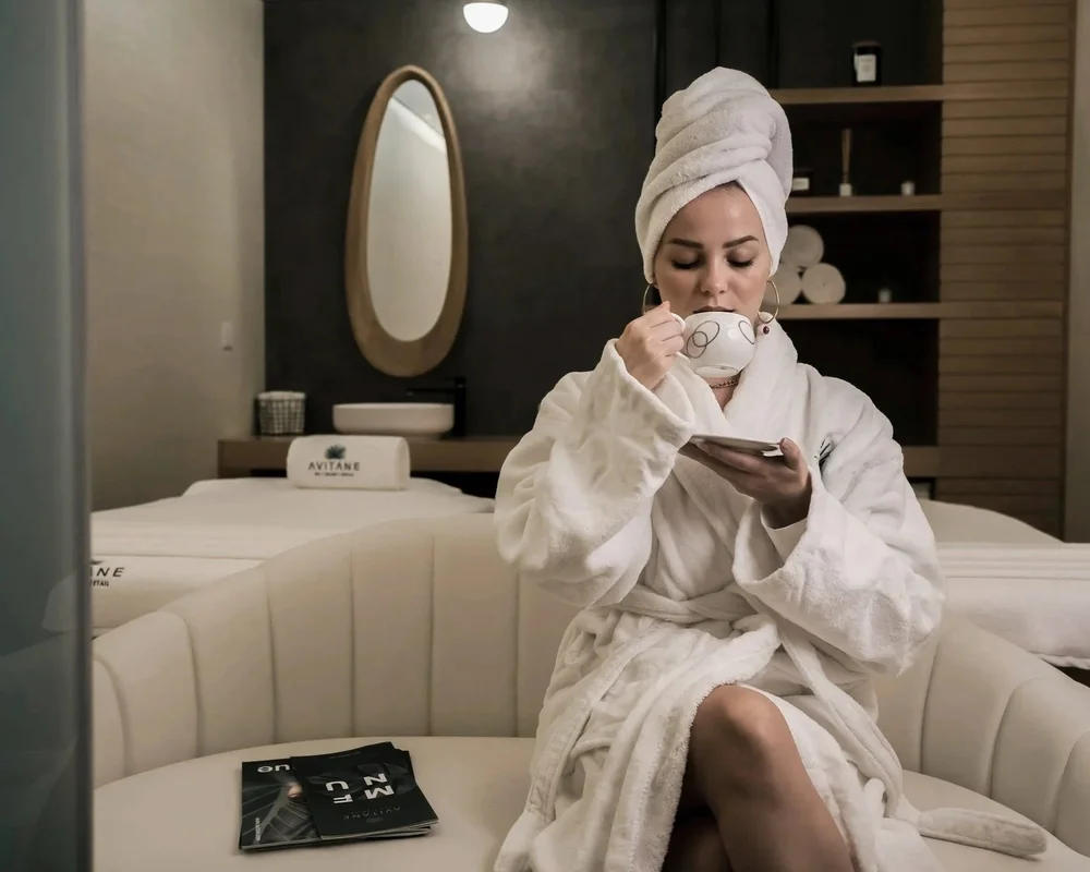 Woman relaxing in a spa robe sipping tea in a wellness lounge, representing SummitView Holdings' vision for future multi-unit brand growth.