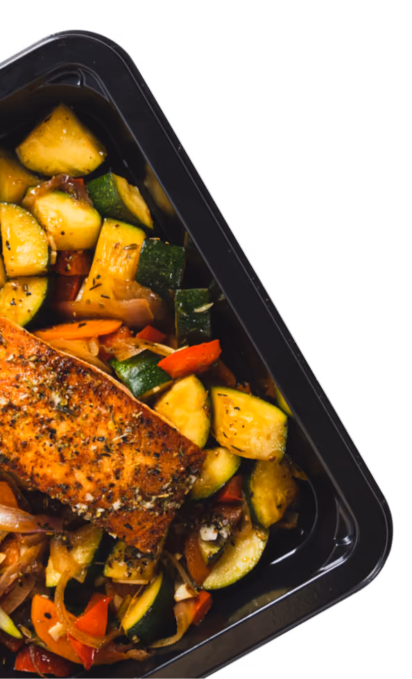 Grilled salmon fillet with seasoned roasted zucchini, red peppers, and onions in a black meal container.