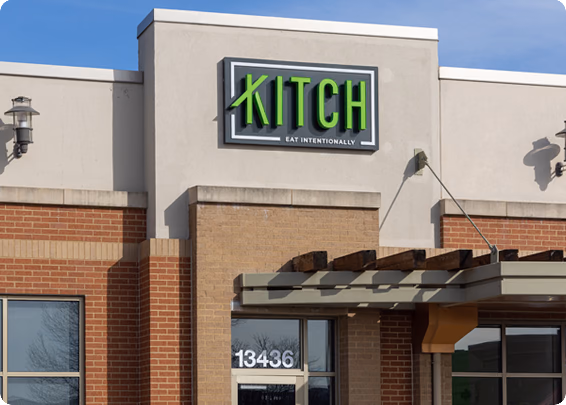 Building facade with green sign reading KITCH and slogan Eat Intentionally above entrance door