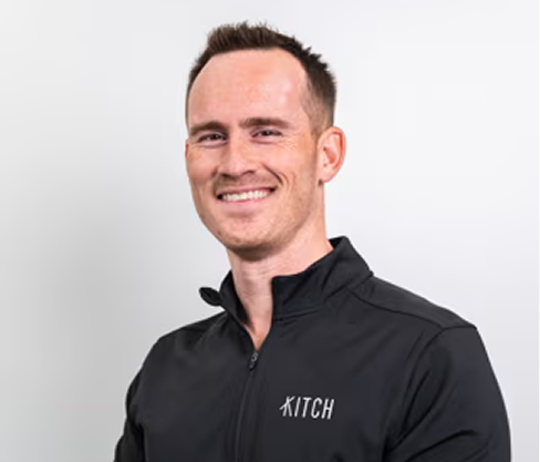 Smiling man with short hair wearing a black Kitch jacket against a plain light background.