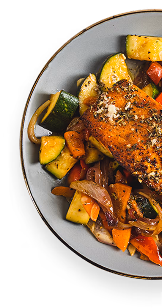 Plate with seasoned grilled salmon and sautéed mixed vegetables including zucchini, carrots, and onions.