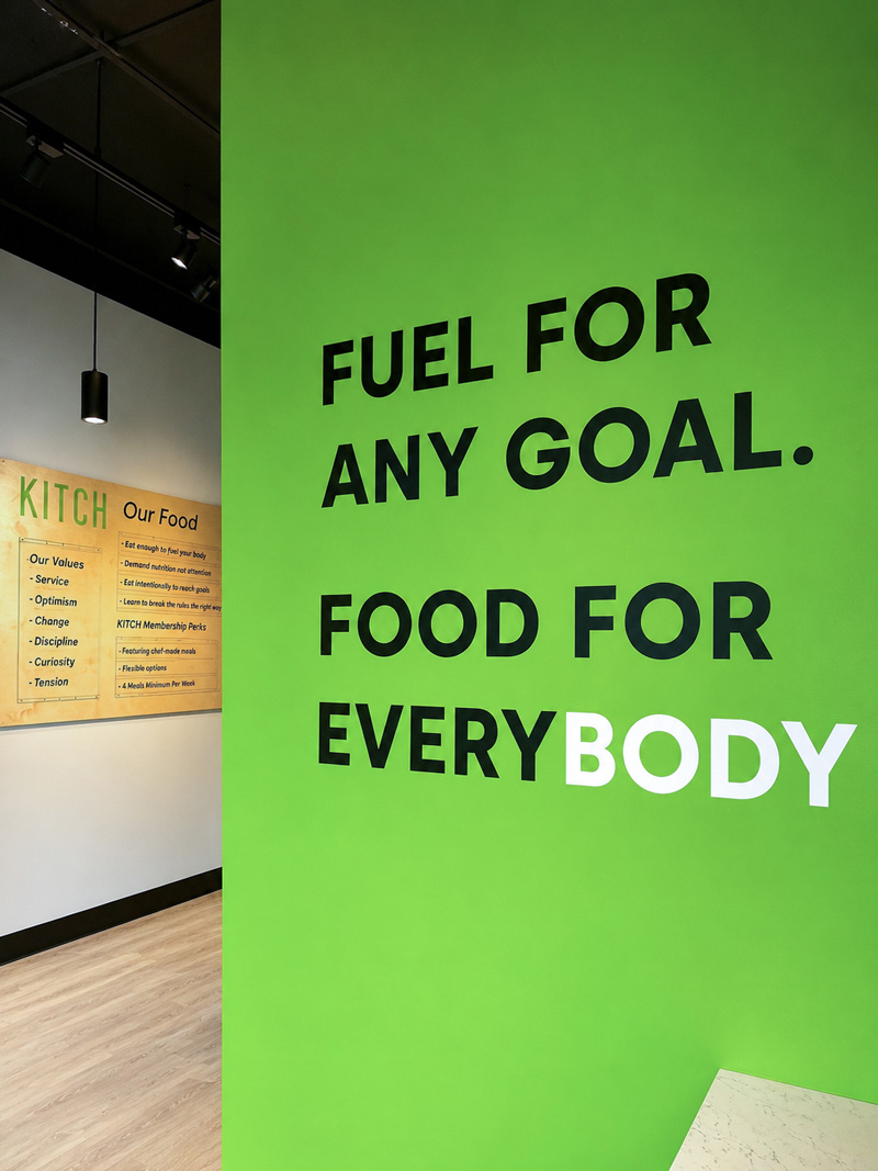 Green wall with black and white text: Fuel for any goal. Food for everybody.