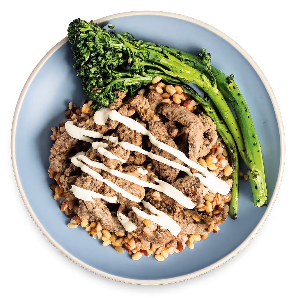Grilled beef strips with cream sauce, lentils, and broccolini served in a blue bowl.