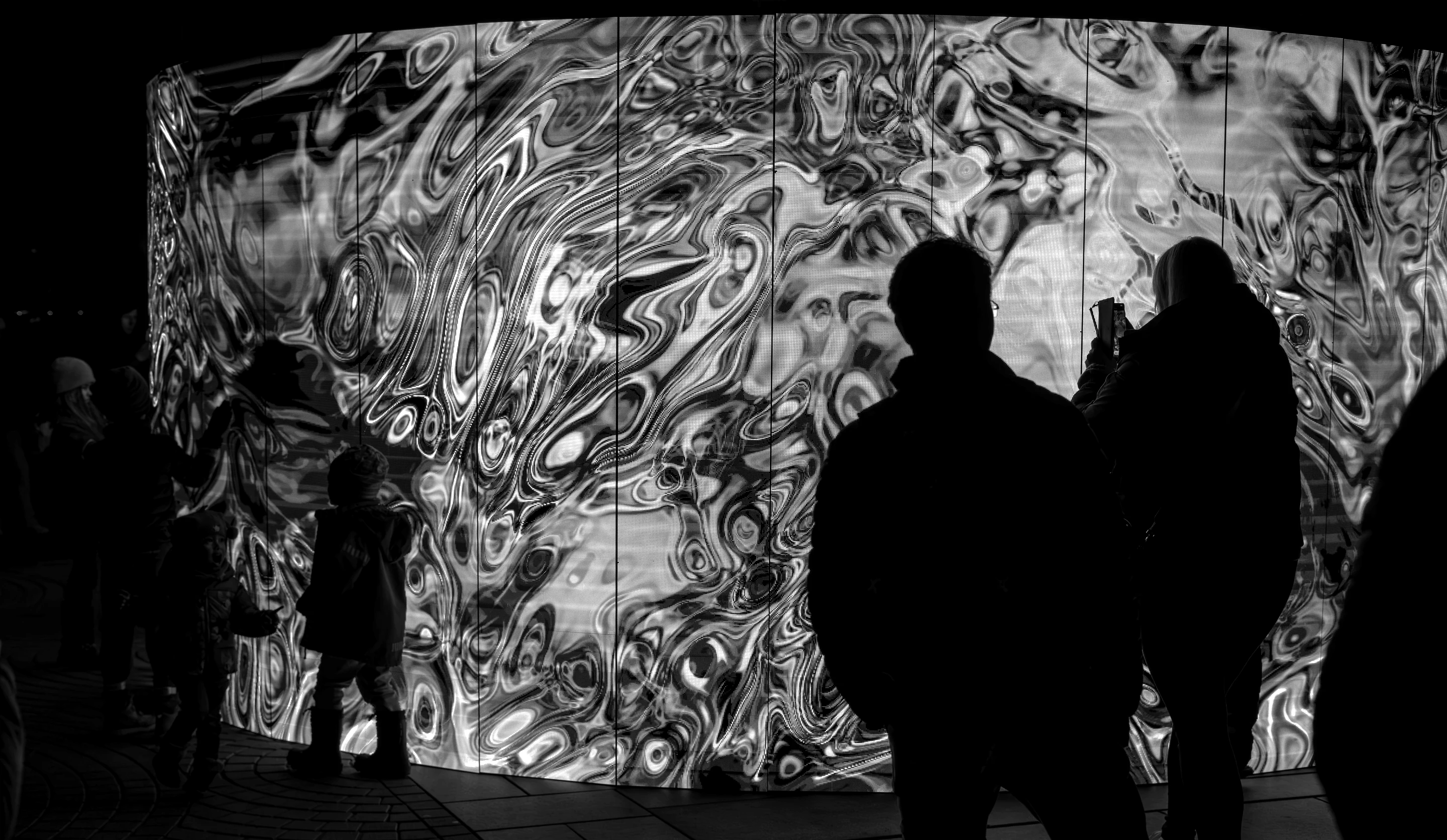 Guests silhouetted against a wall-sized immersive projection