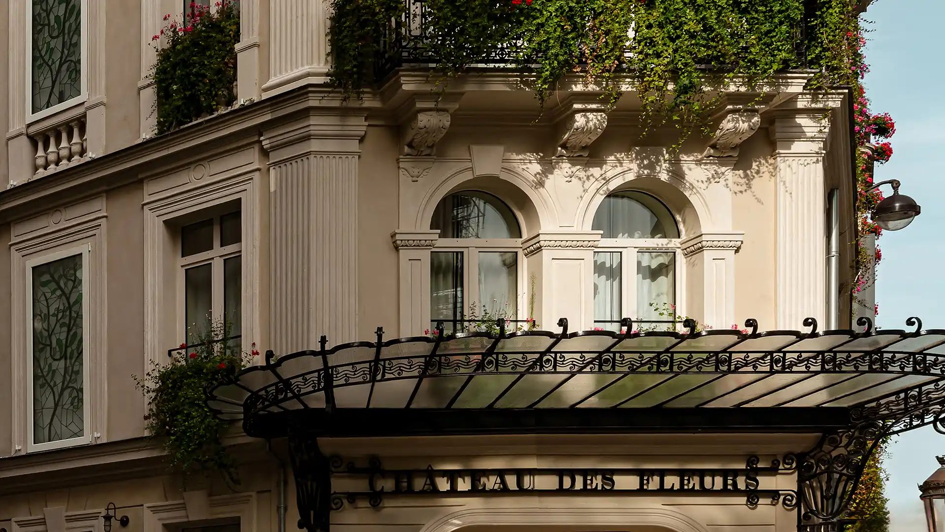 Façade haussmannienne de l'hôtel Château des Fleurs avec marquise en fer forgé et balcons fleuris Paris