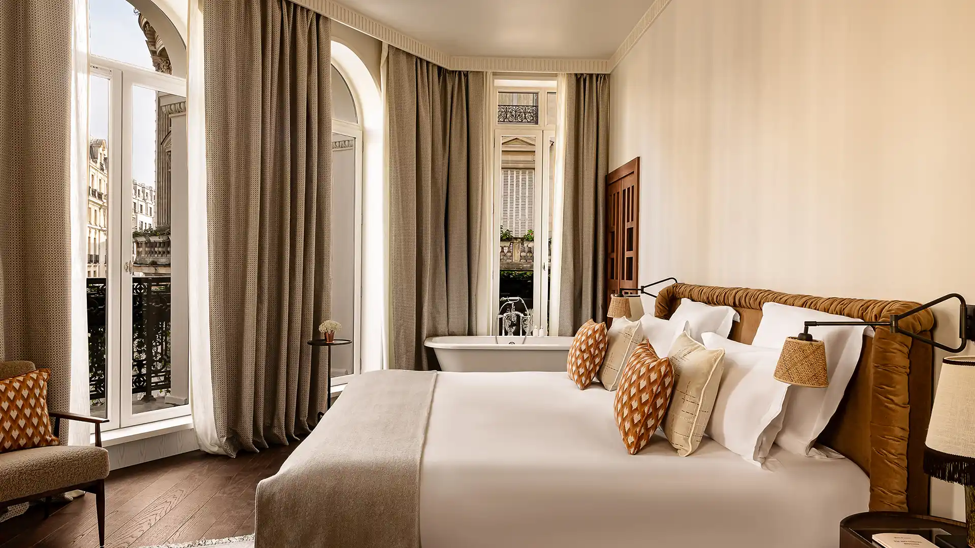 Suite spacieuse avec lit coussins motifs baignoire îlot et vue sur balcons parisiens Château des Fleurs