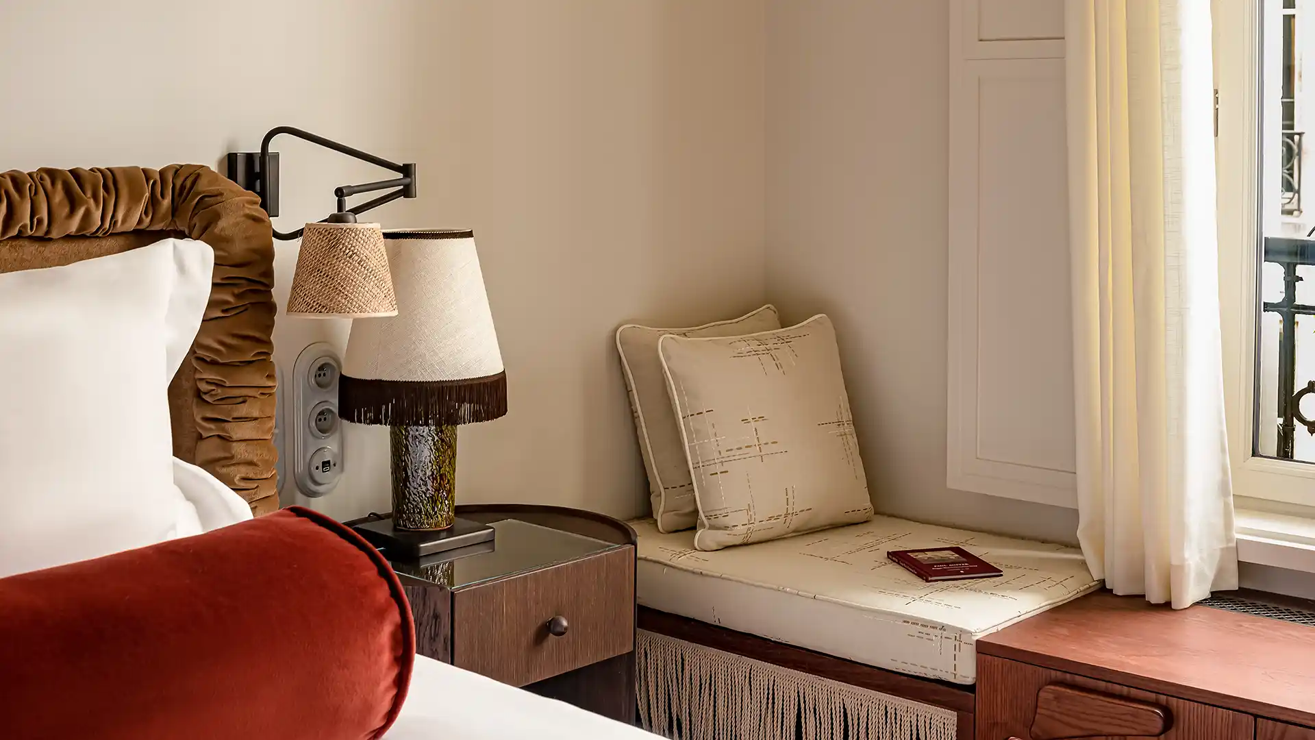 Coin fenêtre avec banquette coussins table de chevet et lampes chambre Château des Fleurs